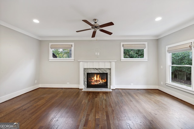 unfurnished living room with a high end fireplace, crown molding, baseboards, and wood finished floors