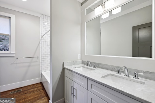 full bath featuring double vanity, wood finished floors, visible vents, and a sink