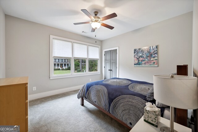 carpeted bedroom with visible vents, baseboards, a closet, and a ceiling fan