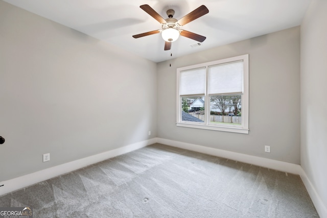 empty room with visible vents, carpet floors, baseboards, and ceiling fan