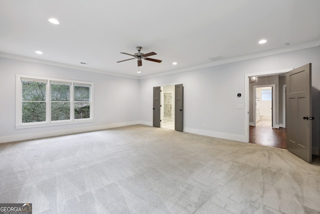 interior space with baseboards, plenty of natural light, light colored carpet, and crown molding