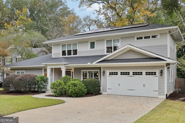 view of front of home featuring solar panels, an attached garage, driveway, and roof with shingles