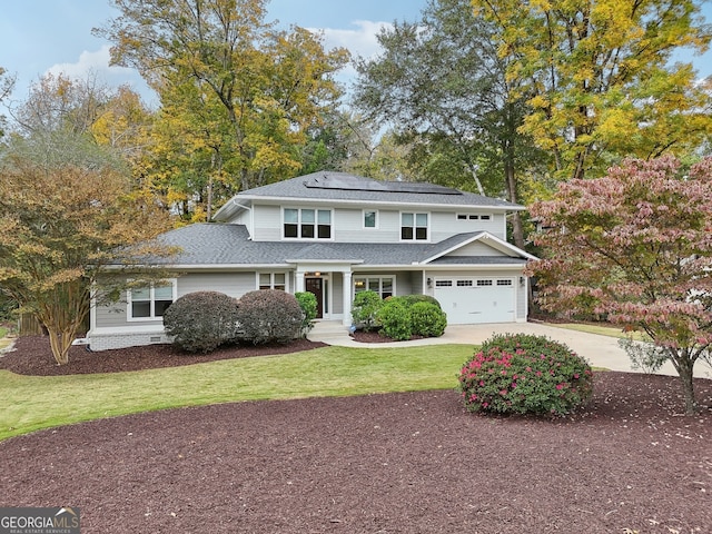 traditional-style home with a garage, roof mounted solar panels, driveway, and a front lawn