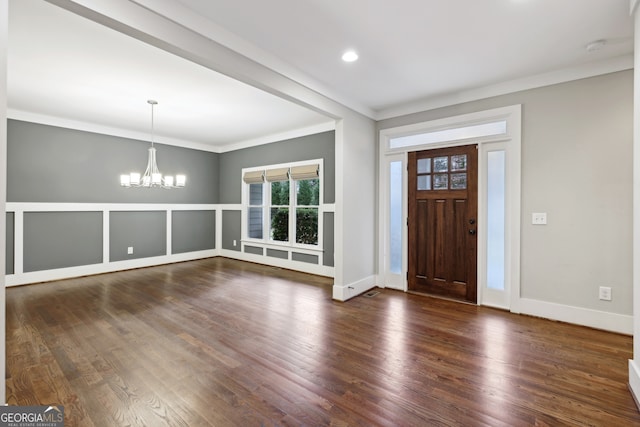 foyer featuring dark wood-style floors, an inviting chandelier, and ornamental molding