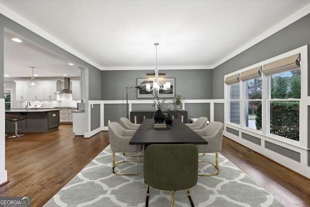 dining area featuring dark wood-style floors, visible vents, an inviting chandelier, and ornamental molding