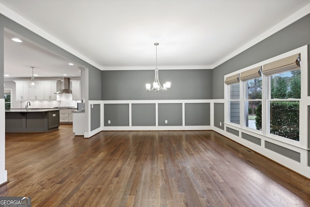 unfurnished dining area with dark wood-style floors, visible vents, an inviting chandelier, and a sink