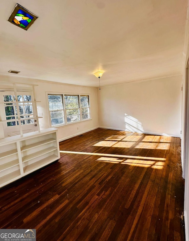 unfurnished room featuring visible vents, baseboards, and hardwood / wood-style floors