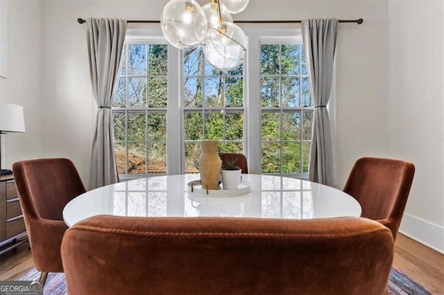 dining room featuring a notable chandelier, wood finished floors, plenty of natural light, and baseboards