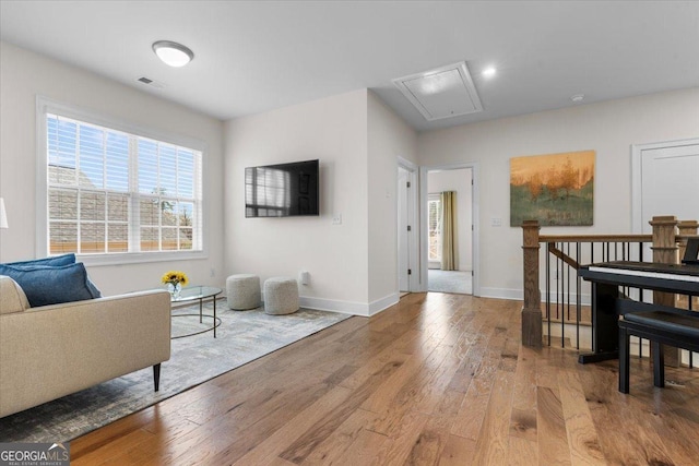 living area with attic access, hardwood / wood-style flooring, baseboards, and visible vents