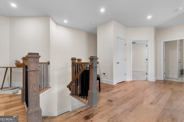 hall featuring recessed lighting, baseboards, an upstairs landing, and wood finished floors