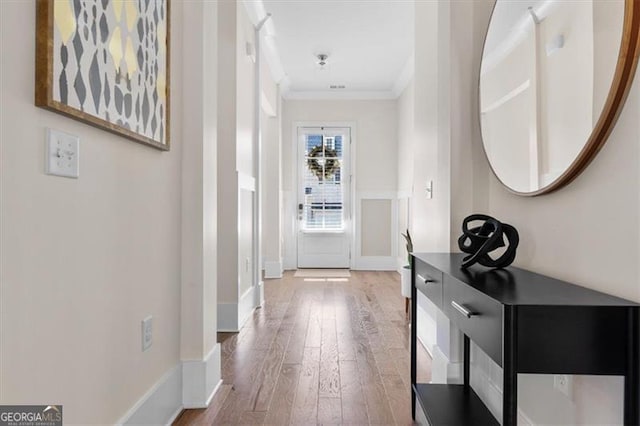 hallway with crown molding, wood finished floors, and baseboards