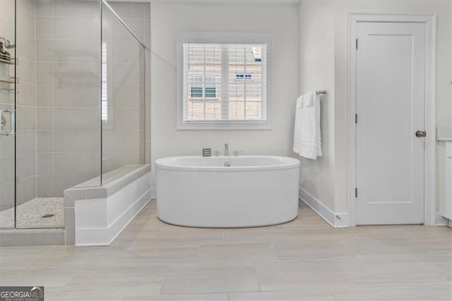 bathroom featuring baseboards, a soaking tub, and a shower stall