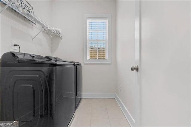 clothes washing area featuring light tile patterned floors, laundry area, washer and dryer, and baseboards