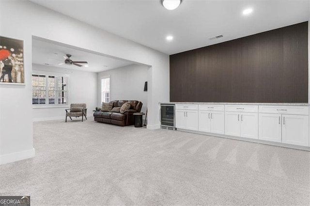 living room featuring visible vents, light carpet, wine cooler, baseboards, and a dry bar