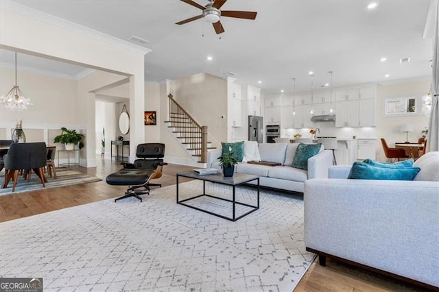 living room featuring recessed lighting, light wood-type flooring, stairs, and ornamental molding