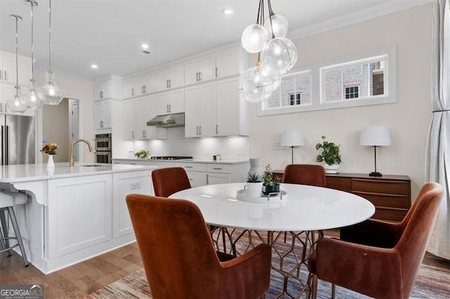 dining room with recessed lighting, ornamental molding, and wood finished floors