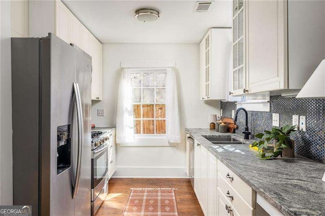 kitchen featuring visible vents, a sink, wood finished floors, appliances with stainless steel finishes, and decorative backsplash