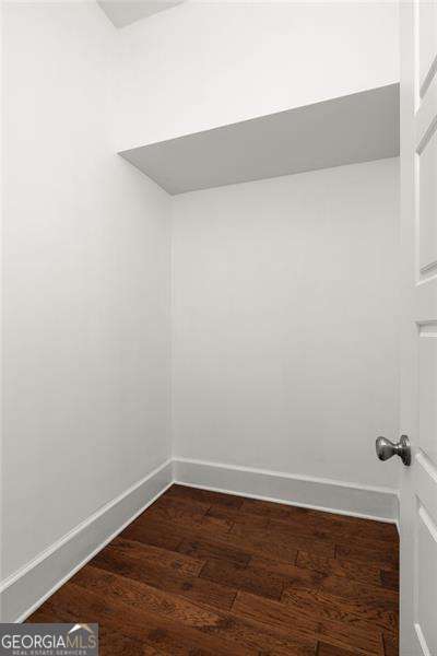 empty room with dark wood-type flooring and baseboards