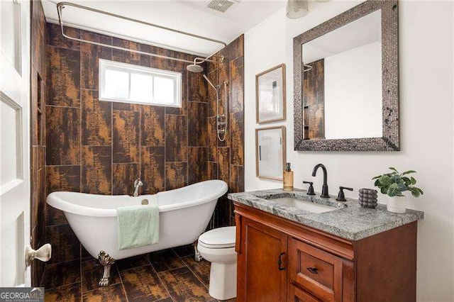 bathroom with visible vents, wood finish floors, toilet, a soaking tub, and vanity