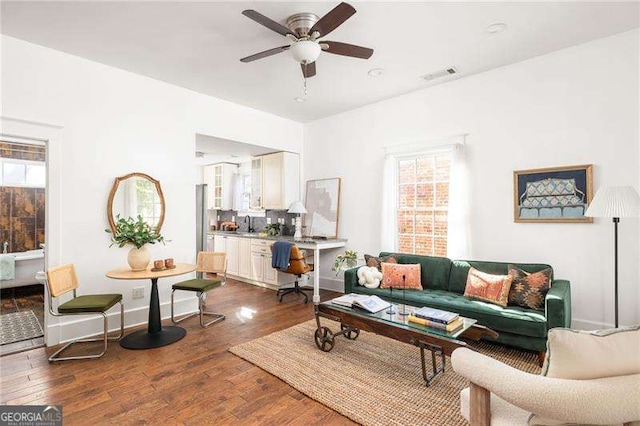 living area with visible vents, dark wood-style floors, and a ceiling fan