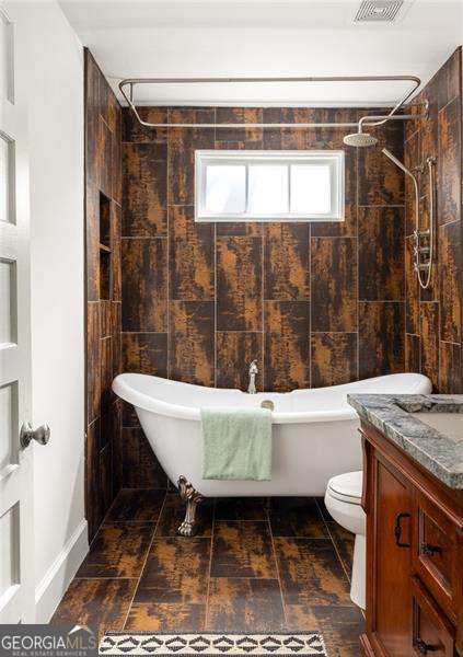 bathroom with a tile shower, toilet, and a freestanding tub