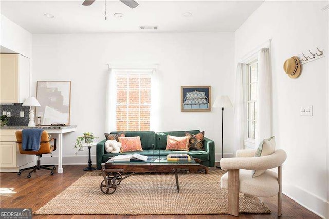 living area with visible vents, a ceiling fan, baseboards, and wood finished floors