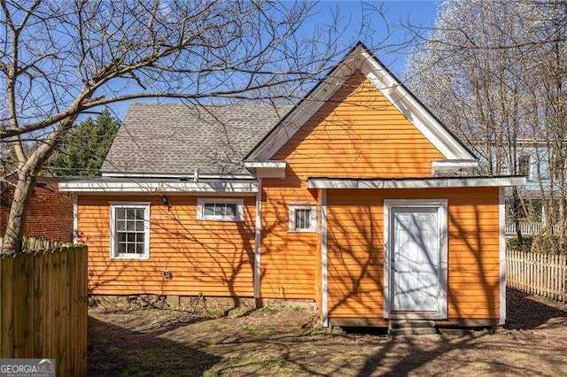 back of house featuring a shingled roof and fence