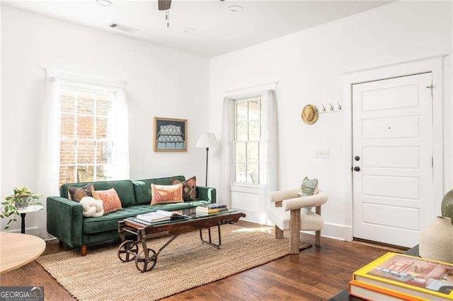 living area with ceiling fan, visible vents, baseboards, and wood finished floors