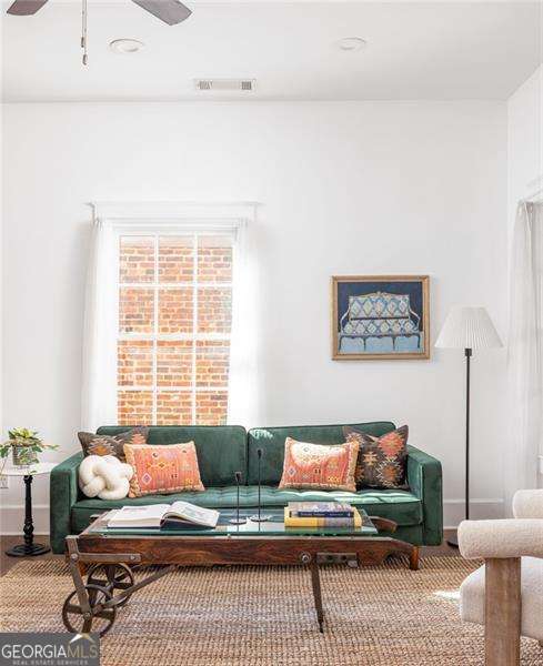 living room with visible vents, baseboards, and a ceiling fan