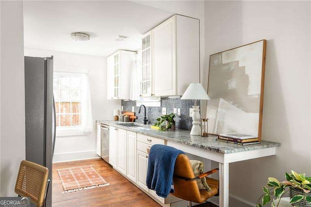 kitchen with white cabinetry, freestanding refrigerator, a sink, decorative backsplash, and stainless steel dishwasher