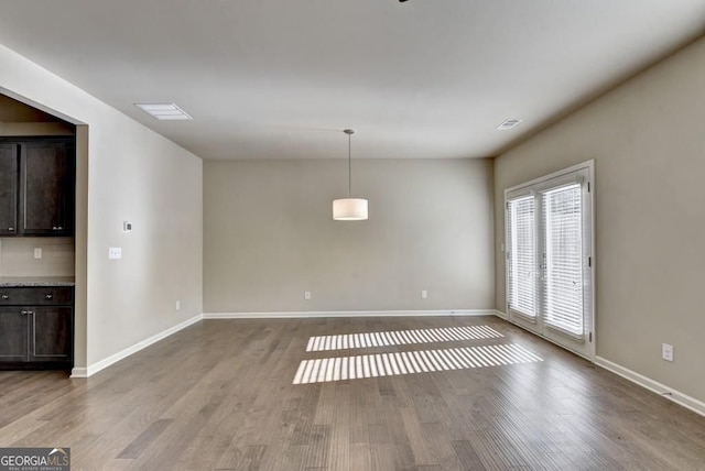 unfurnished dining area featuring visible vents, baseboards, and wood finished floors