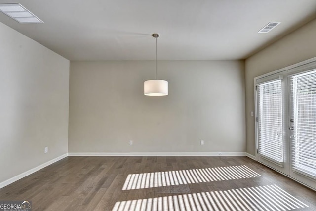 unfurnished room featuring visible vents, baseboards, and wood finished floors