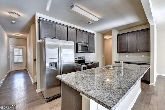 kitchen with light stone counters, decorative backsplash, appliances with stainless steel finishes, and a sink