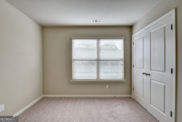 unfurnished bedroom featuring carpet flooring, baseboards, visible vents, and a closet