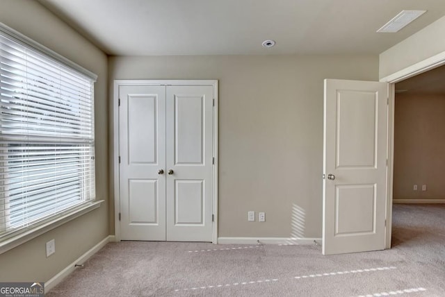 unfurnished bedroom with a closet, visible vents, baseboards, and carpet