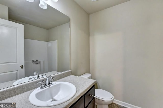 bathroom featuring toilet, vanity, and baseboards