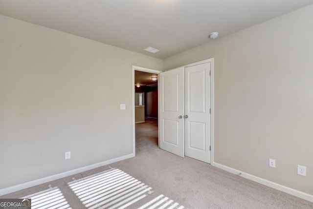 unfurnished bedroom with baseboards, light carpet, and a closet