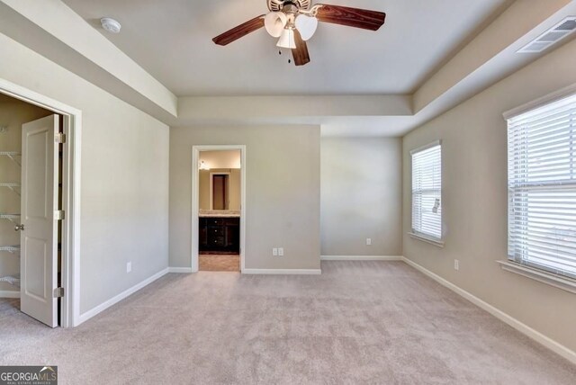 unfurnished bedroom with a walk in closet, baseboards, visible vents, and light carpet