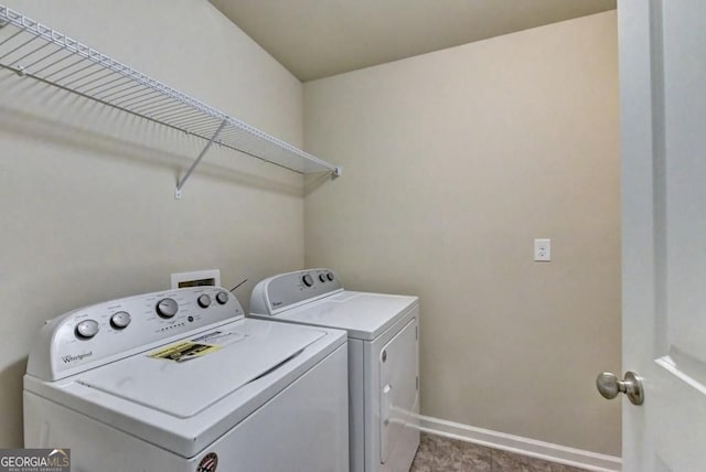 clothes washing area with laundry area, baseboards, and washer and clothes dryer