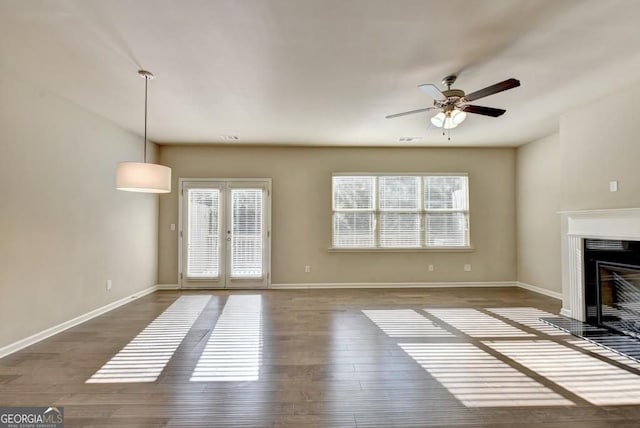 unfurnished living room featuring visible vents, ceiling fan, baseboards, a fireplace with flush hearth, and wood finished floors