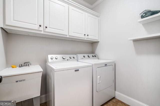 laundry area with crown molding, separate washer and dryer, a sink, baseboards, and cabinet space