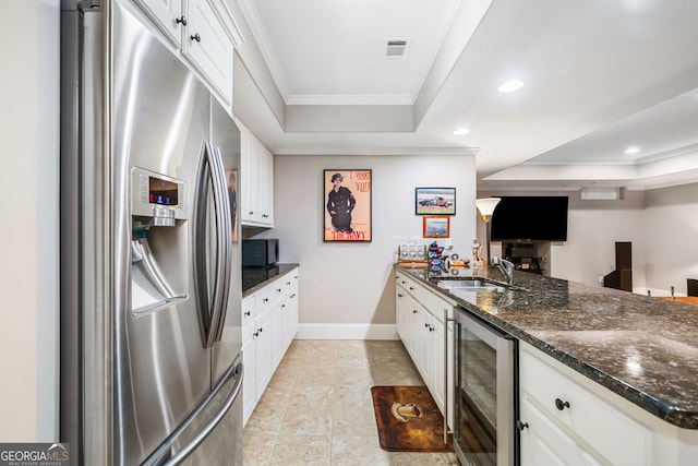 kitchen featuring a tray ceiling, beverage cooler, crown molding, and stainless steel fridge