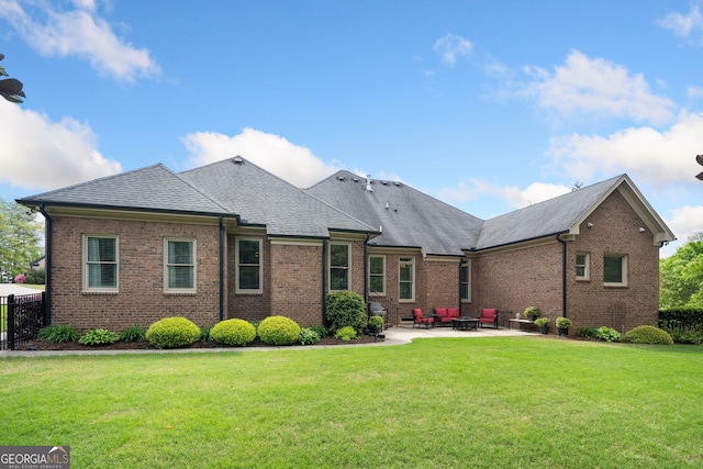 back of property featuring brick siding, a yard, a shingled roof, and a patio