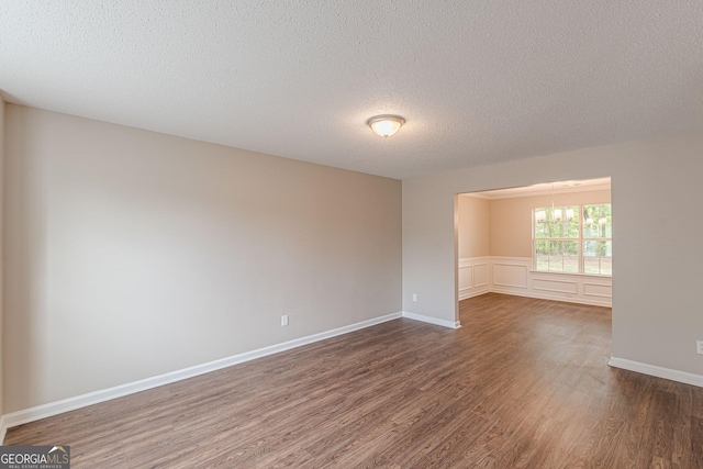 empty room featuring a chandelier, a textured ceiling, and dark wood finished floors