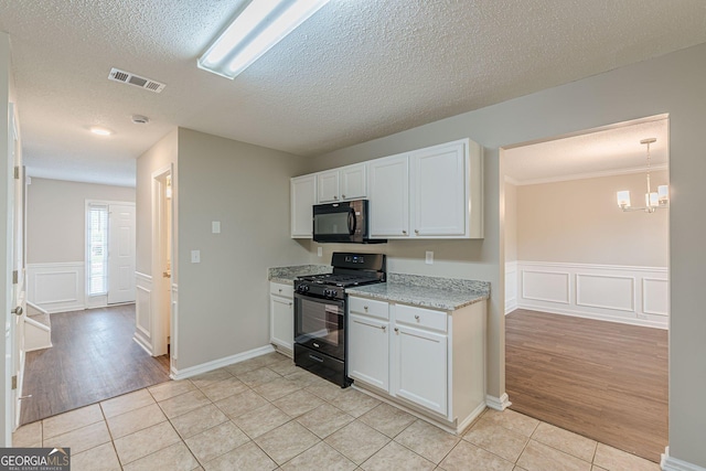 kitchen with light tile patterned floors, black appliances, visible vents, and a textured ceiling