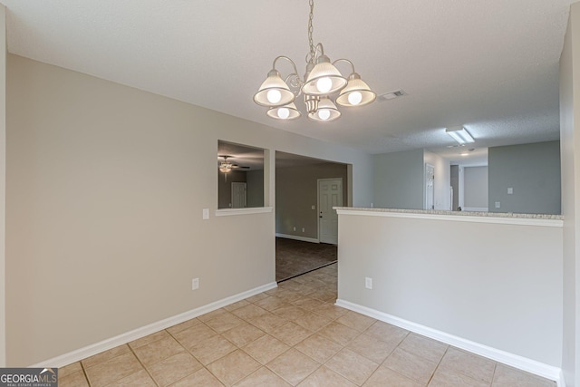 unfurnished room with baseboards, visible vents, light tile patterned flooring, and ceiling fan with notable chandelier