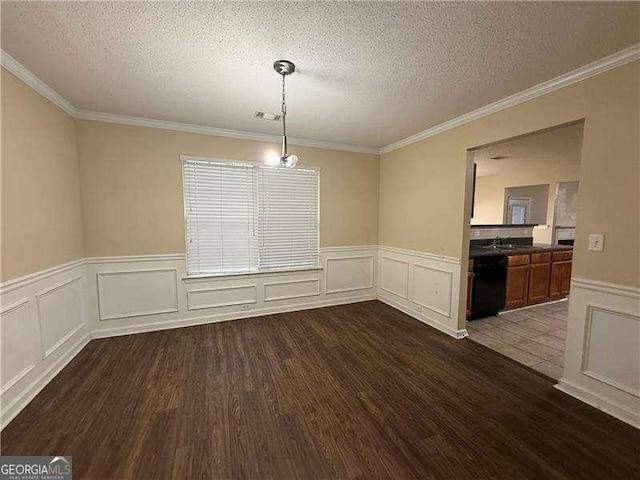 unfurnished dining area with a wainscoted wall, visible vents, dark wood finished floors, ornamental molding, and a textured ceiling