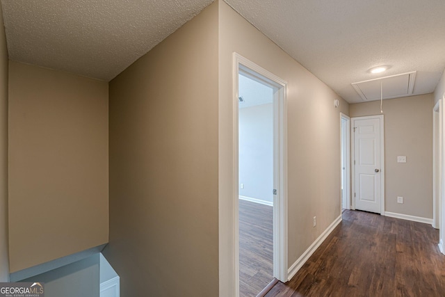 hallway featuring attic access, dark wood finished floors, and baseboards
