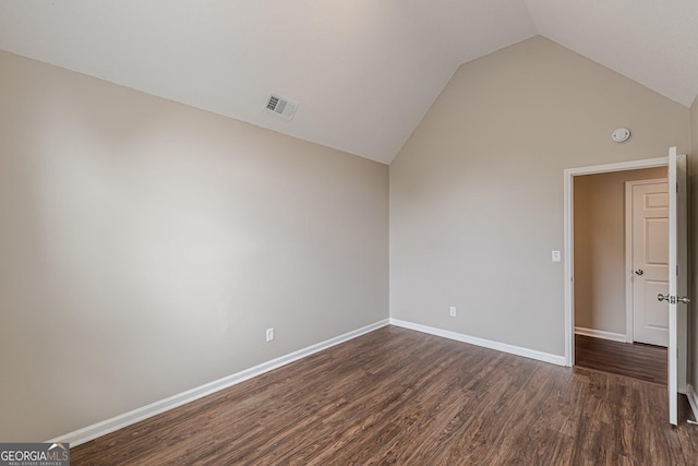 spare room with visible vents, baseboards, lofted ceiling, and dark wood-style floors
