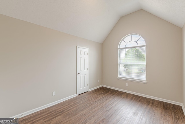 unfurnished room featuring baseboards, vaulted ceiling, and wood finished floors
